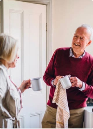 Elderly man and woman talking with cups in their hands