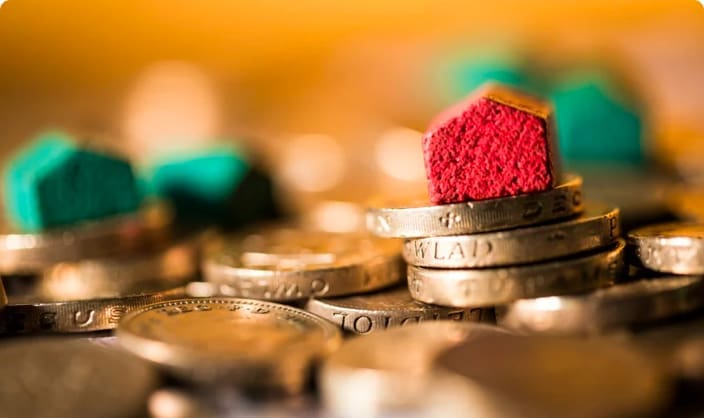 Wooden model house on top of pound coins