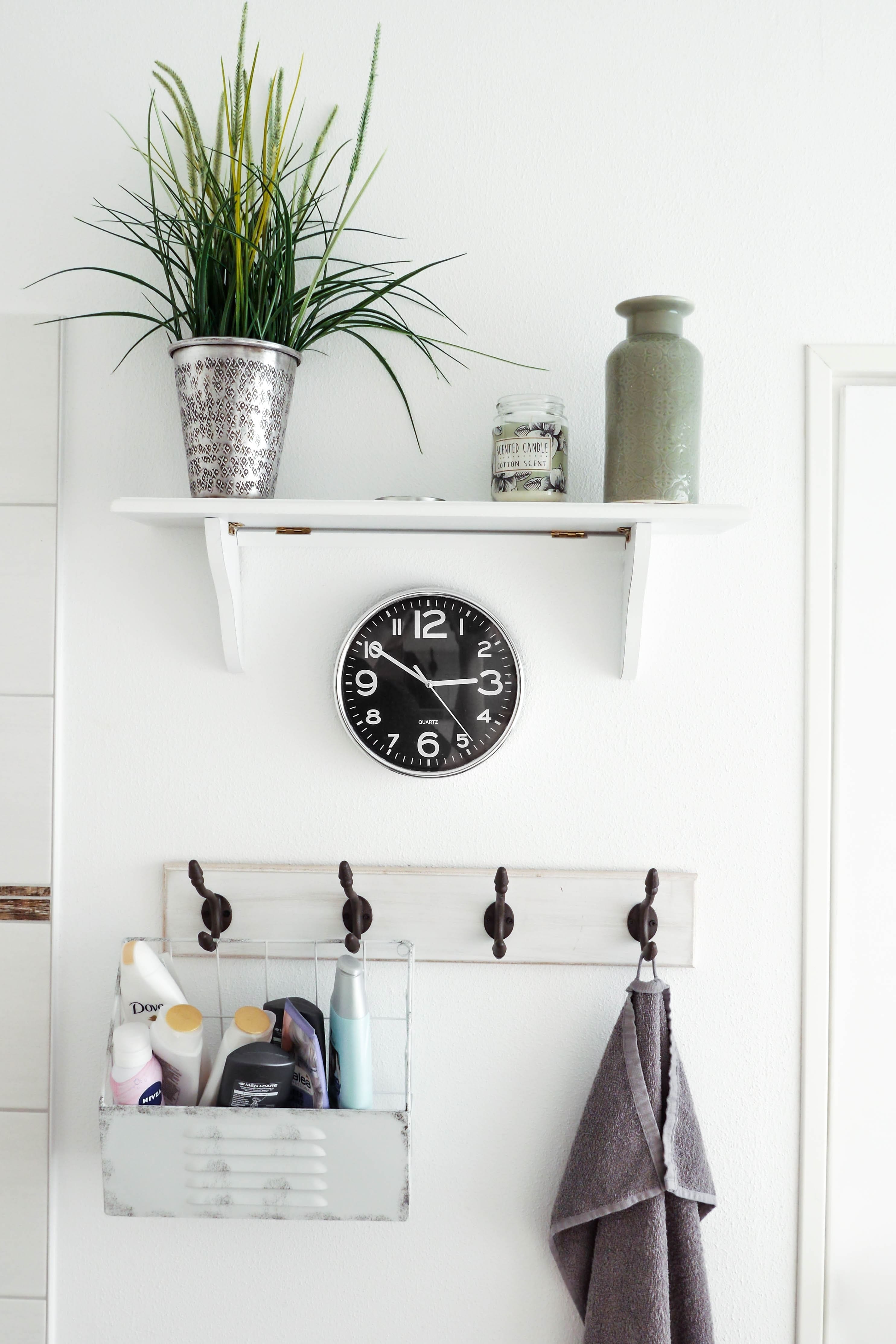 a shelf above a clock and coat hooks