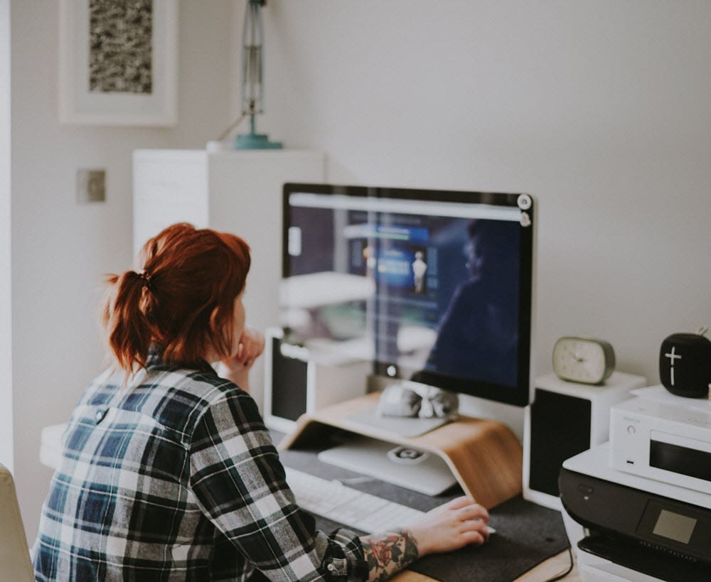 Woman with tattoos using computer in a clean and white office space