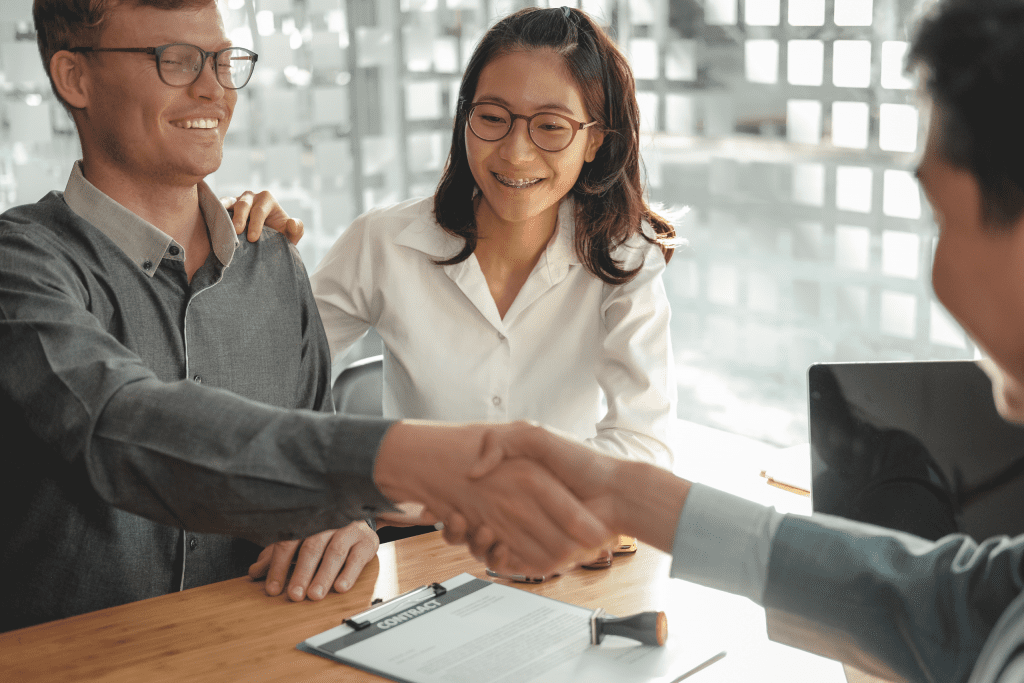 a couple shaking hands with a man over a contract