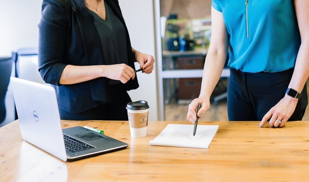 two women discussing a contract on a table