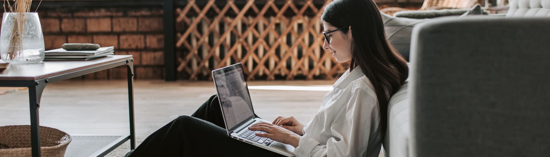 a woman sat on the floor working on her laptop